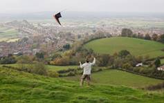 A man flying a kite on top of a hill