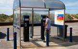 A man putting coins in a machine at a pay and display car park