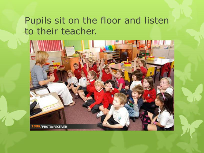 Pupils sit on the floor and listen to their teacher